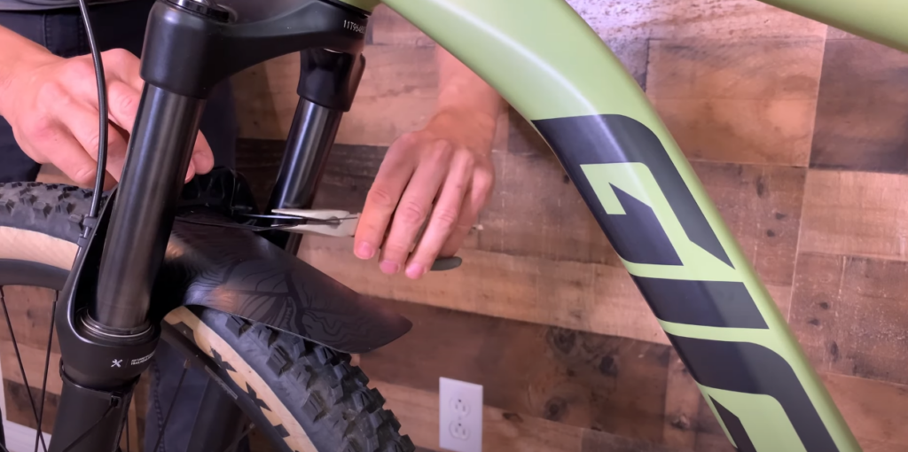 Hand installing a mudguard onto a bicycle's front wheel