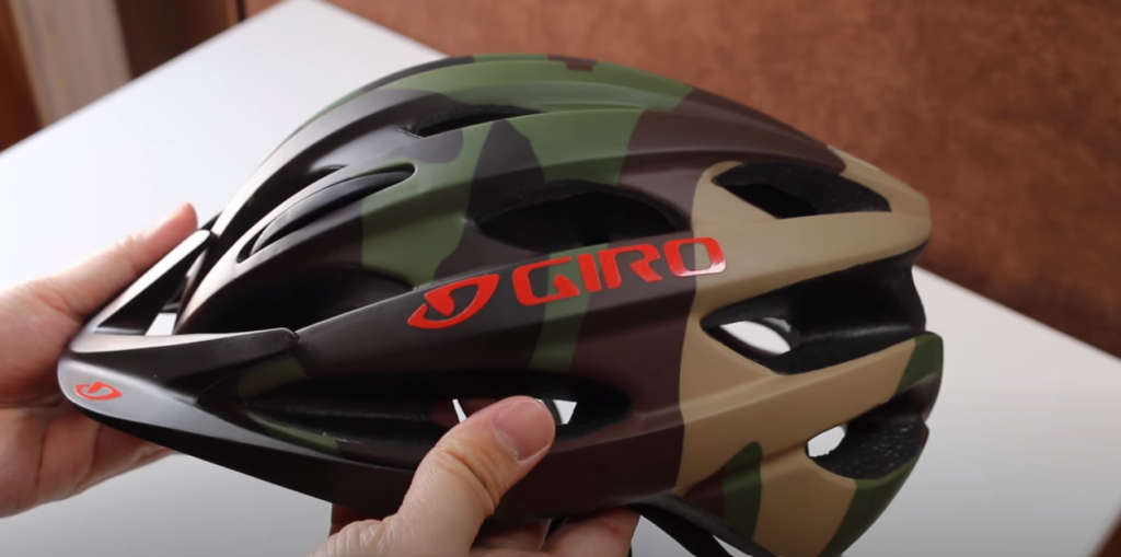 A hand holding a camouflage Giro Revel Bike Helmet