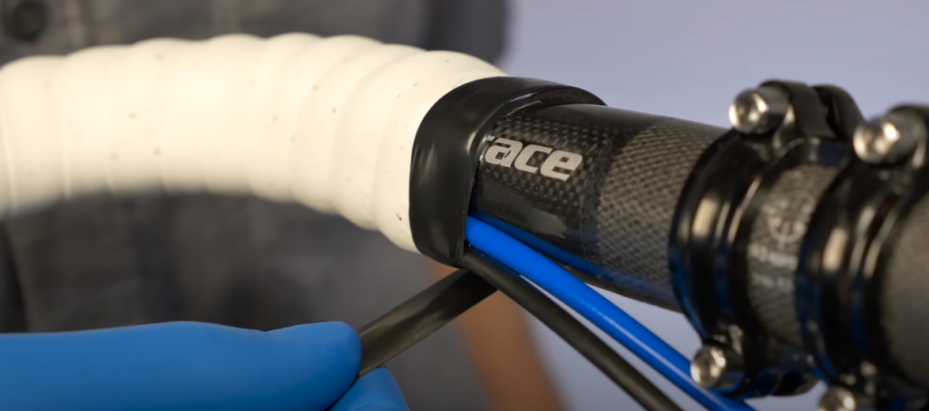 Person wrapping bicycle handlebars with white and black tape