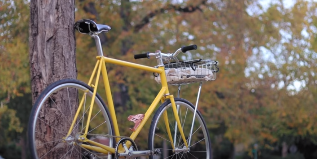 a city bike with a yellow frame and a metal basket on the front