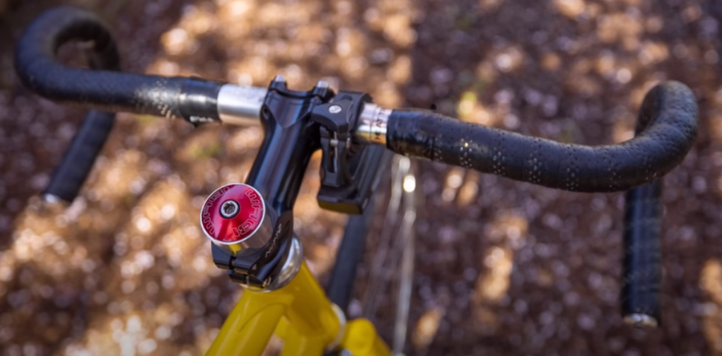 black handlebars of a bike with a contrasting crimson-colored headset