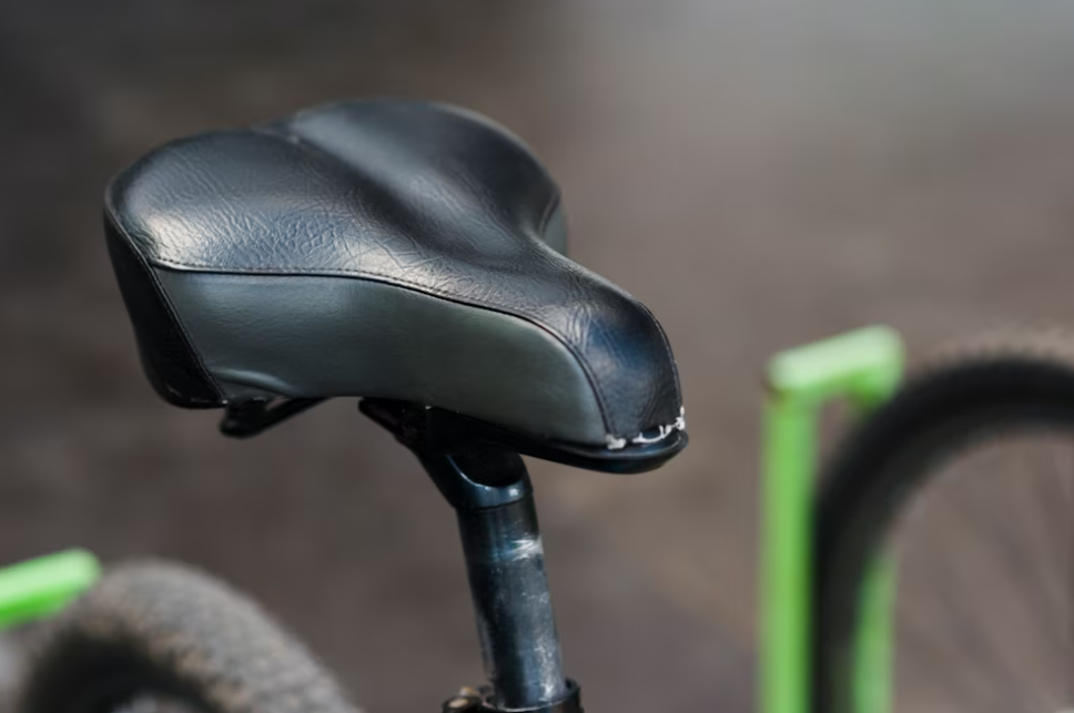 black saddle of green bike and blurred background behind